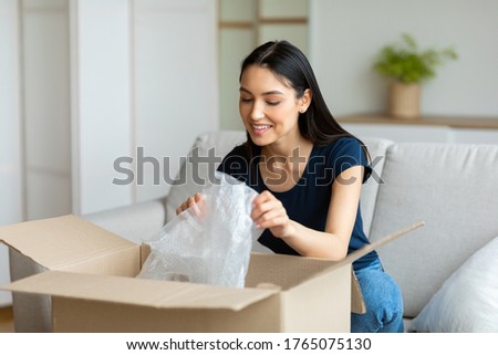 Delivery Service Concept. Cheerful Customer Girl Unpacking Box Smiling Sitting On Couch At Home