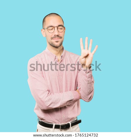 Young man making a number four gesture