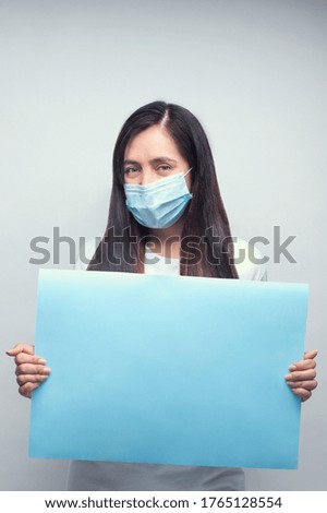 A young female doctor in a medical mask holding a blank board-COVID-19