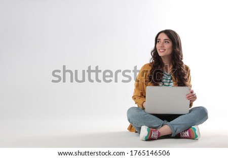 Young woman sitting with laptop on white background
