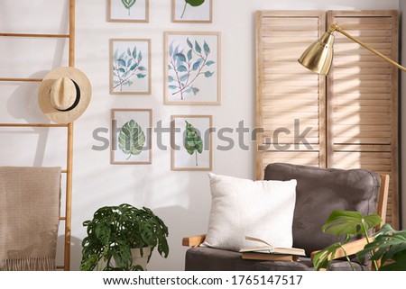 Stylish room interior with different artworks and armchair