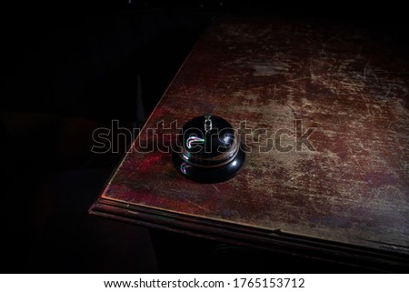 Calling service bell on wooden table with toned lights on dark background. Hotel reception bell, service bell on the table, selective focus