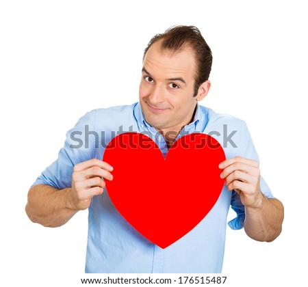 Closeup portrait of happy smiling handsome funny looking man, holding large red heart to chest daydreaming of women in love, isolated on white background. Positive emotions, facial expression feelings