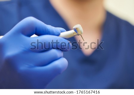 A close photo of a hand of a dentist who holds a dental diamond drill in the turbine stainless handpiece. Royalty-Free Stock Photo #1765167416
