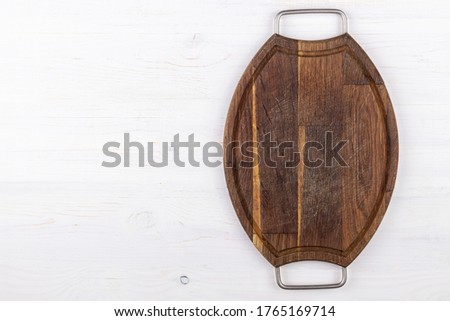 Brown cutting board on a white wooden background. View from above. Place for text.