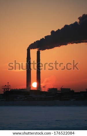 Photo of two smoking chimneys against the sun