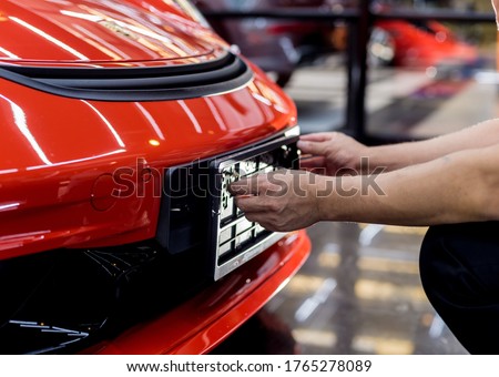 Technician changing car plate number in service center. Royalty-Free Stock Photo #1765278089