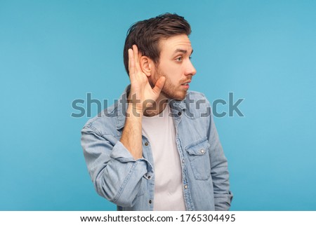 What? I can't hear! Portrait of man in worker denim shirt holding hand near ear and listening carefully, having hearing problems, deafness and misunderstanding in communication. studio shot isolated Royalty-Free Stock Photo #1765304495