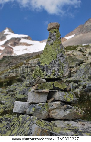 
stacked pyramid stones that mark a mountain path, with a snowy peak in the background
