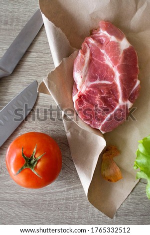 Raw pork steak on old paper and vegetables