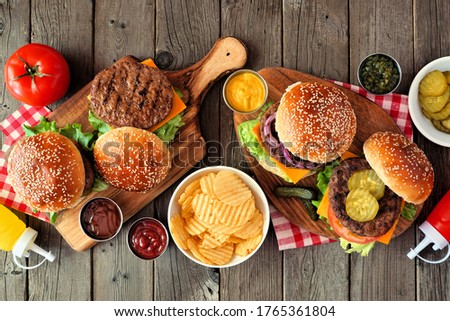 BBQ hamburger table scene. Top view over a dark wood background.