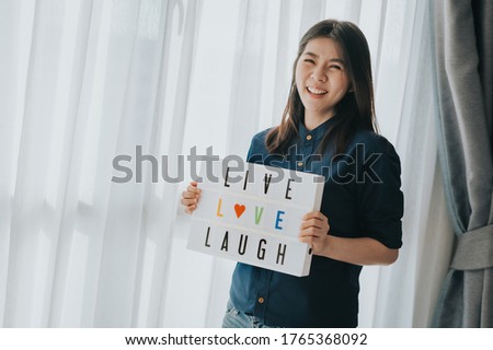 Happy Asian Woman holding live love laugh sign lightbox indoor