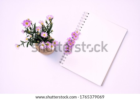 Workplace top view, flat lay, office desk table, empty spiral notebook, violet daisy flowers composition, European Michaelmas Daisy, business background, studying concept, memory