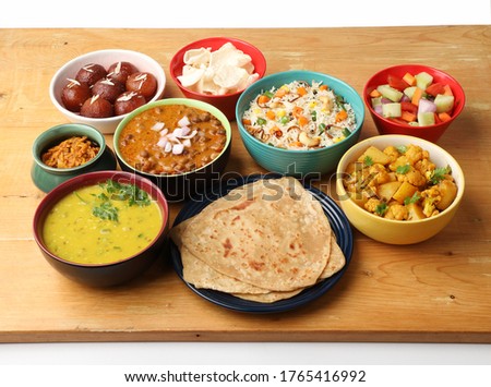 Indian whole meal with yellow dal, vegetable pulao, chapati,gulab jamun, salad, papad, pickle, chana masala curry and aloo gobi Royalty-Free Stock Photo #1765416992