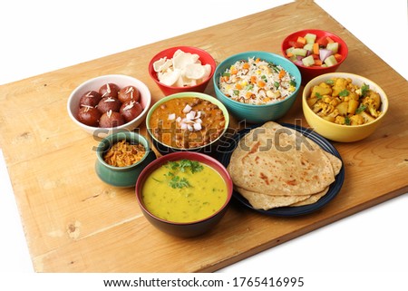 Indian whole meal with yellow dal, vegetable pulao, chapati,gulab jamun, salad, papad, pickle, chana masala curry and aloo gobi Royalty-Free Stock Photo #1765416995