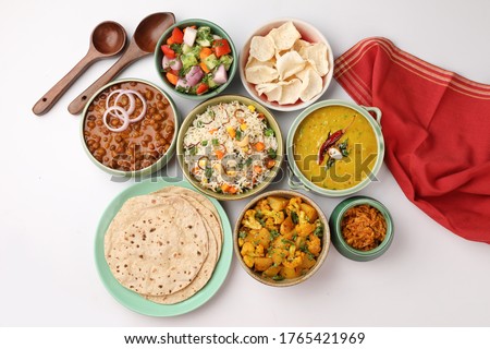 Indian whole meal with yellow dal, vegetable pulao, chapati,gulab jamun, salad, papad, pickle, chana masala curry and aloo gobi Royalty-Free Stock Photo #1765421969