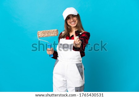 Painter woman over isolated blue background showing and lifting a finger