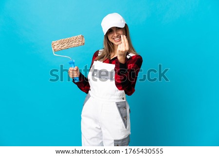 Painter woman over isolated blue background making money gesture