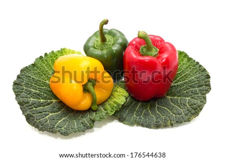 Yellow, green and red pepper on green leafs isolated on white background.