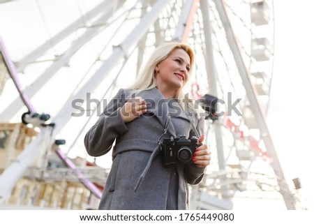 Young woman walking outdoors on the city street near ferris wheel smiling cheerful.