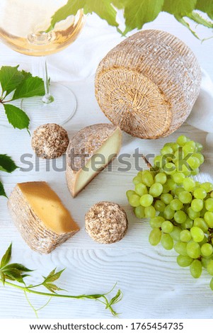 Hard cheese with grapes on a light background. Copy space.Top view.Vertical photo.