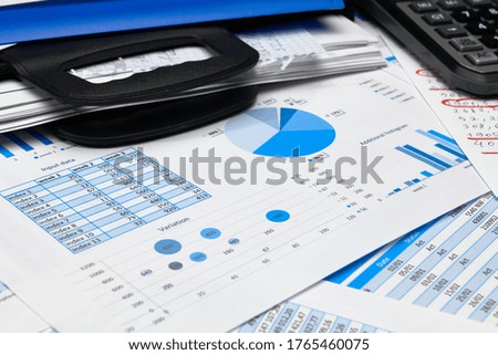 business office desk closeup - financial reports, analysis and accounting, set of documents, tables and graphs, various items for bookkeeping, calculator