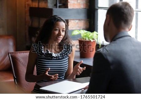 African applicant answer questions at job interview meeting in cafe with employer. Human resources, staffing process. Client and representatives communication, make offer sell company services concept Royalty-Free Stock Photo #1765501724