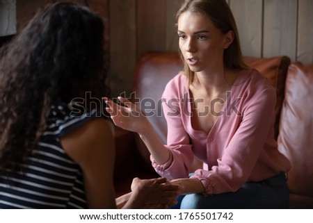 While Caucasian girl share personal life troubles African best friend hold hand express attention show empathy supporting her. Clinical psychologist identify problems, provide help to client concept Royalty-Free Stock Photo #1765501742
