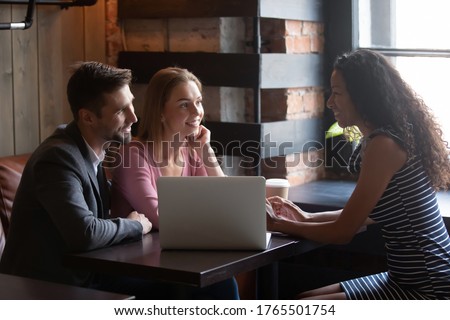 Wedding planner meet with couple in cafe discuss moments of upcoming event. Photographer show professionals quality of pictures to potential clients. Diverse colleagues talk during lunch break concept