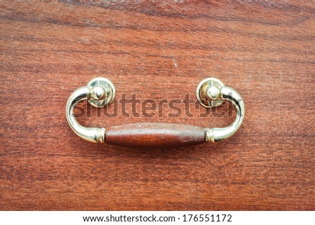 An antique drawer handle on a wooden drawer