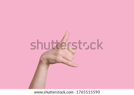 Caucasian woman hand making a call me gesture. on pink background