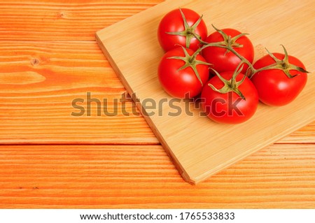 Bunch of tomatoes on a wooden vegetable cutter on a wooden background