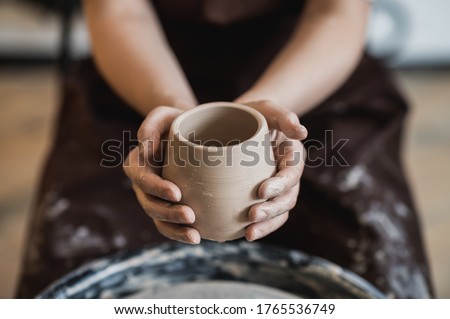 Cuts of product with wire. Craftsman hands making pottery bowl. Woman working on potter wheel. Family business shop sculpts pot from clay. Royalty-Free Stock Photo #1765536749