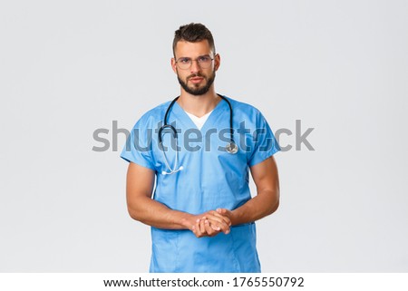 Healthcare workers, medicine, covid-19 and pandemic self-quarantine concept. Serious-looking determined, professional doctor or intern, nurse in blue scrubs and glasses, talking to patient