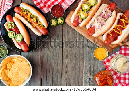 BBQ hot dog frame. Overhead view table scene with a dark wood background. Copy space.