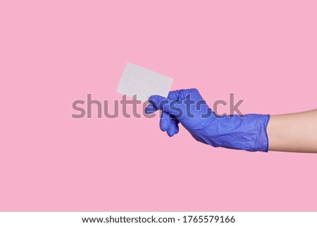 Hand in latex glove holds a business card, credit card or blank paper isolated