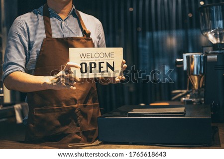 cropped shot of smiling barista holding sign open in coffee shop.cafe owener open and welcome customer.