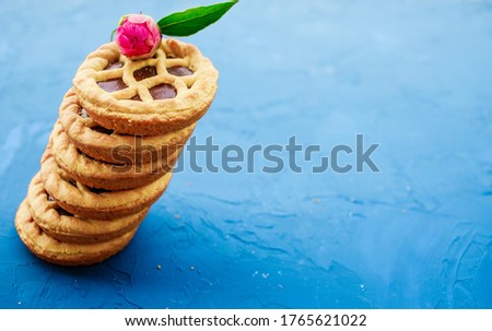 Shortbread cookies with chocolate and pink flower on top on a blue textured background.