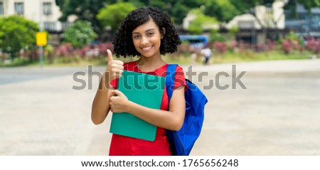 Successful hispanic female college student with backpack outdoor in city in summer