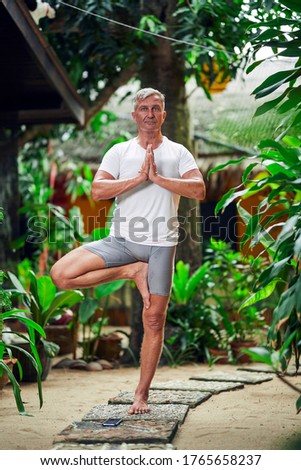 A man practice yoga in the green tropical jungle