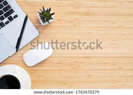 Modern wood pattern office desk table with wireless computer mouse, laptop and coffee cup with supplies. View from above with copy space. business workplace concept.