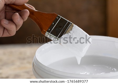 man holds brush in his hand ready to paint with white paint Royalty-Free Stock Photo #1765689377