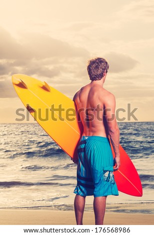 Surfer on the beach at sunset in Hawaii