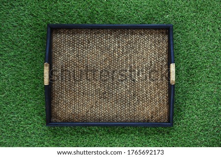 Square weave wood tray with black holders on green glass background