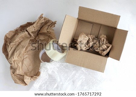 Corrugated box. Duct tape, paper for packaging inside the box. Bubble wrap. Tools for packaging products on a white background. Packer. Royalty-Free Stock Photo #1765717292
