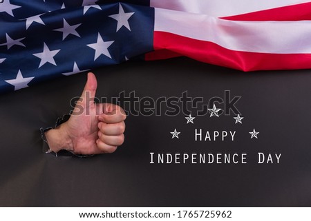 Independence Day or Memorial Day. Man's hand with American flags on black paper background.Copy space, Flat lay.