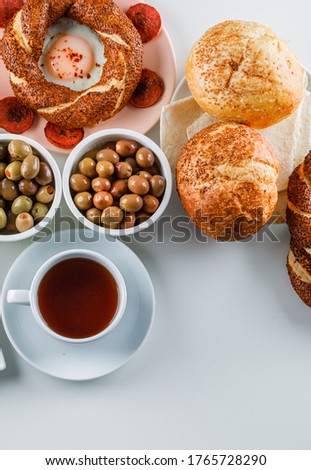 Set of a cup of tea, turkish bagel, olive, bread and eggs with sausage in a plate on a white background. top view.