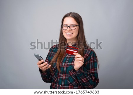Photo of young woman using smartphone and credit card.