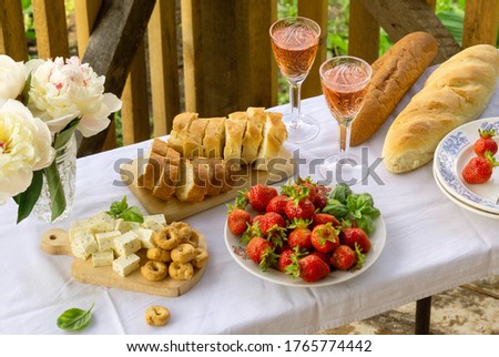 Summer picnic table with various snacks and rose wine outdoors