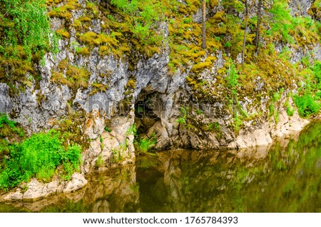 Cave in a rock near a flowing river.